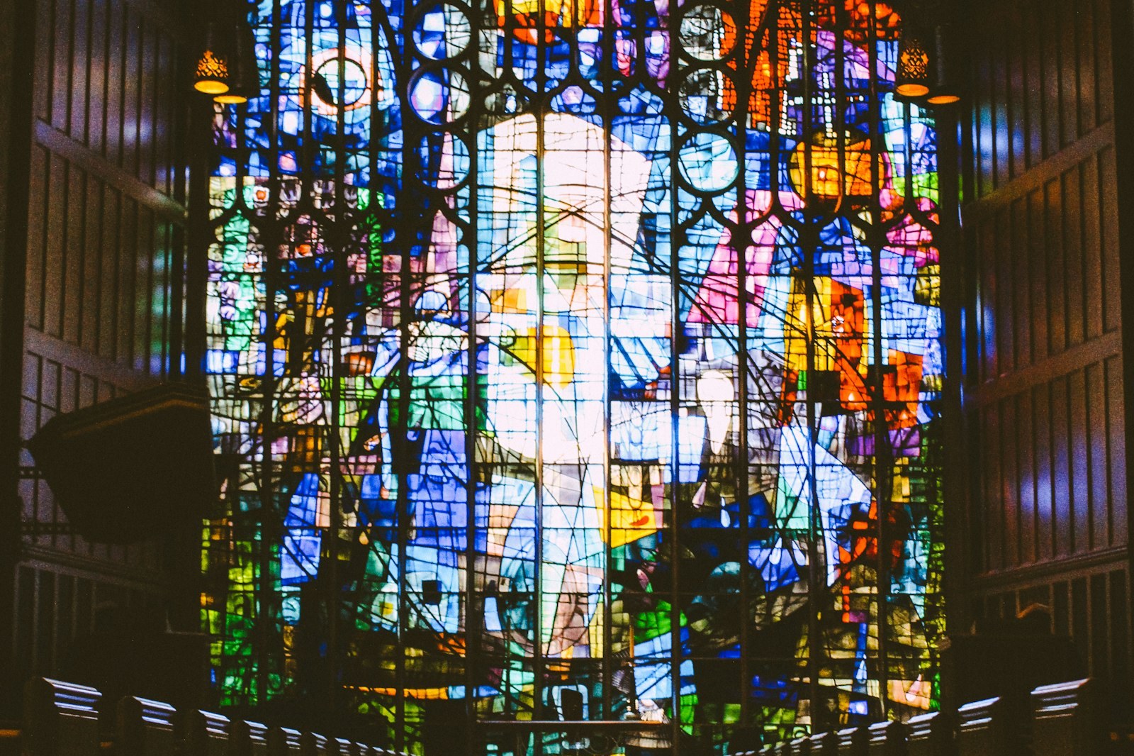 A church aisle leading to a large stained glass window