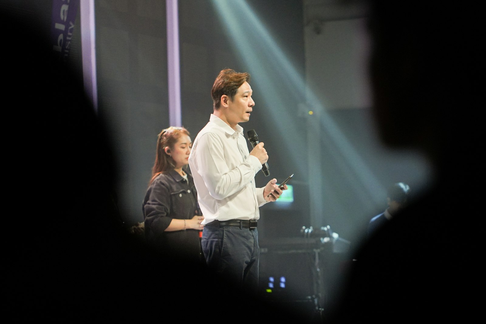 A man speaking into a microphone on a spotlit stage