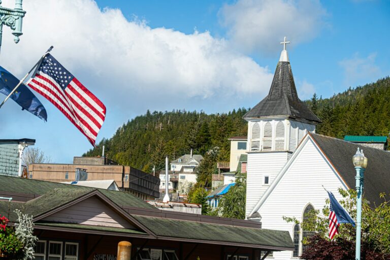 An American flag flying beside a white church with a steeple