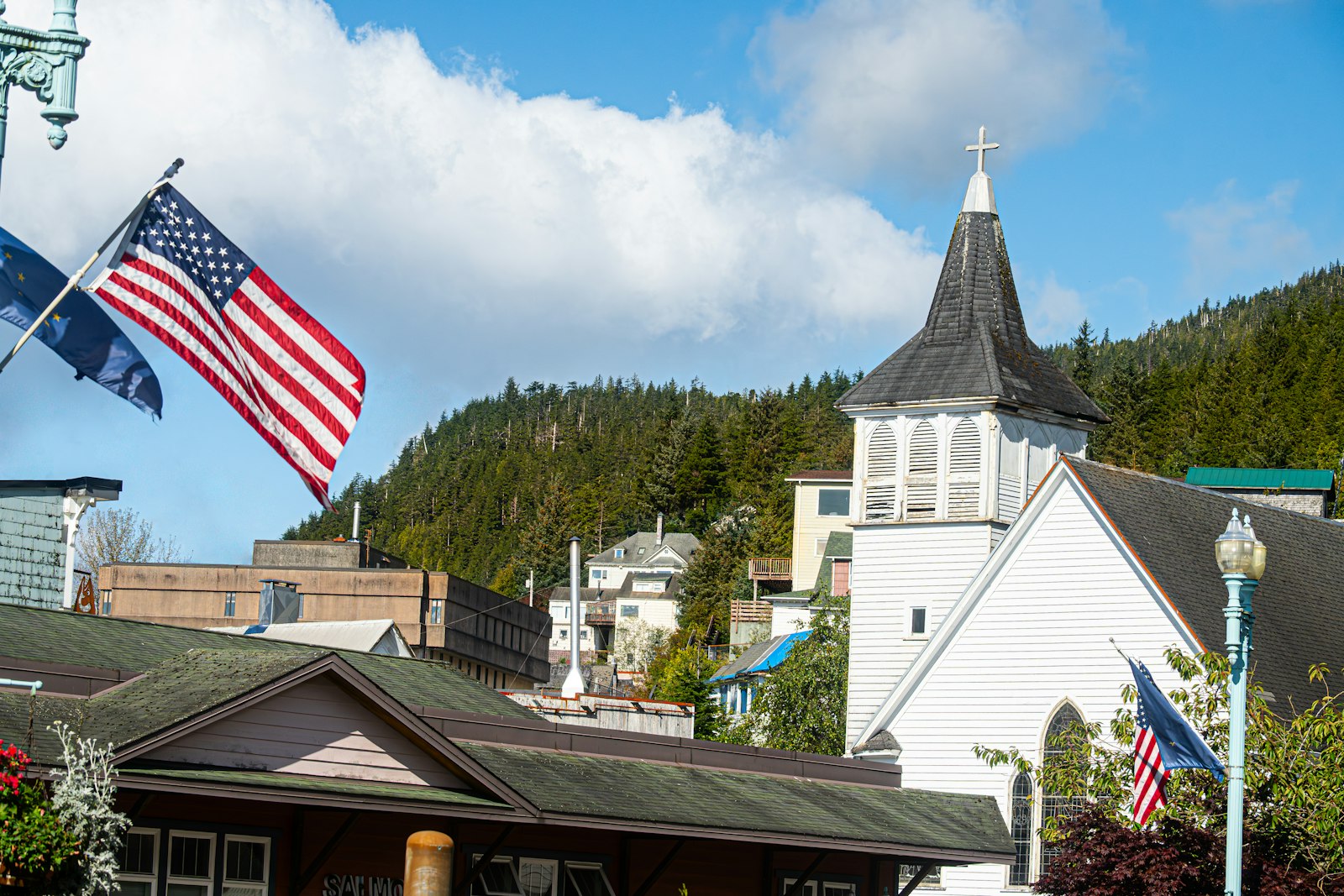 An American flag flying beside a white church with a steeple