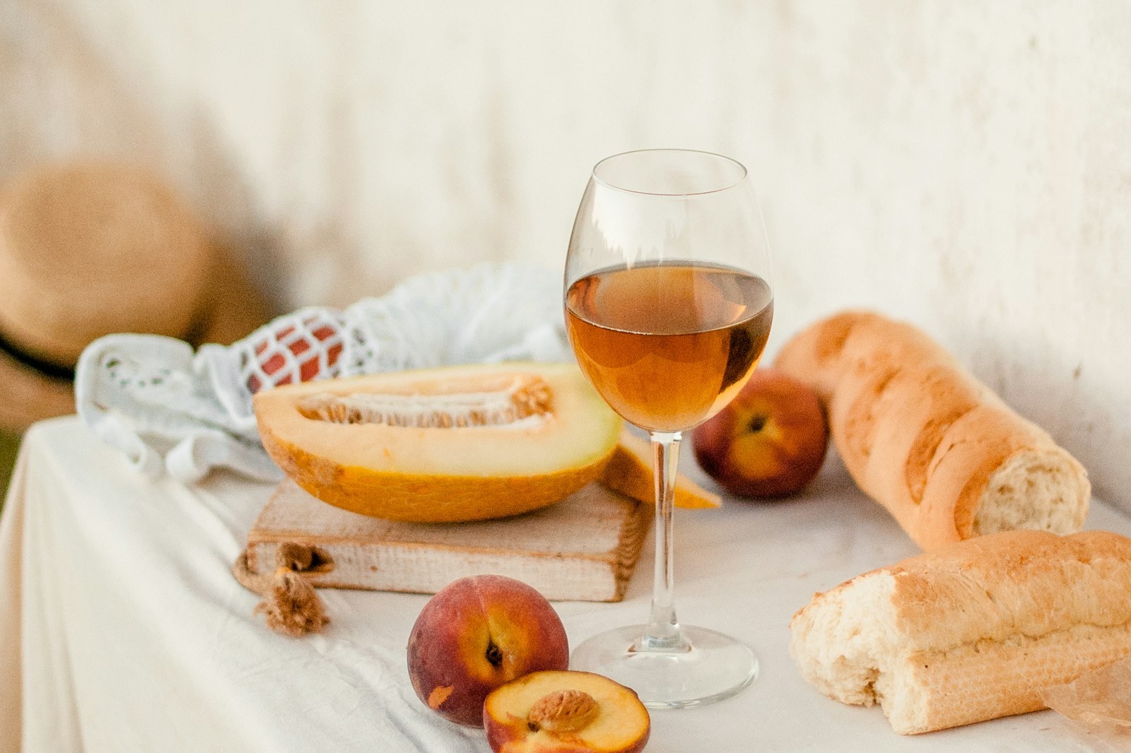 Bread, a glass of wine, and fruit on a cloth-covered table
