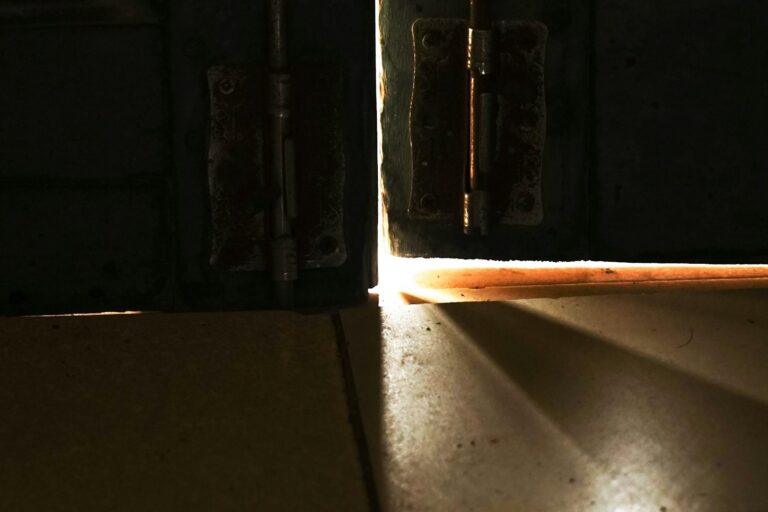 A door open to a sliver of warm light