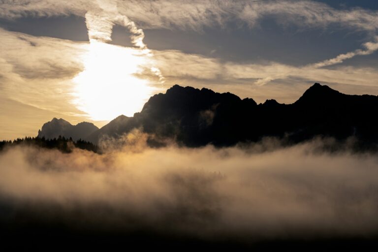 Sunrise breaking through clouds over misty mountains